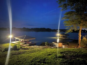 A lakeside property at dusk with a covered dock, a small cabin, and a large open pavilion.