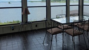 Habitación con ventanas amplias que ofrecen vista a un lago y tierra distante.