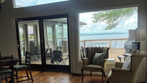 Amplia habitación con suelo de madera, ventanas grandes y vistas a un lago.