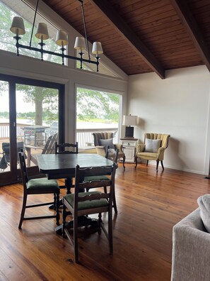 A spacious dining area with a wooden table and chairs, a lamp, and a view of the outdoors.