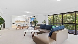 A modern living room with a sofa, coffee table, and dining area.
