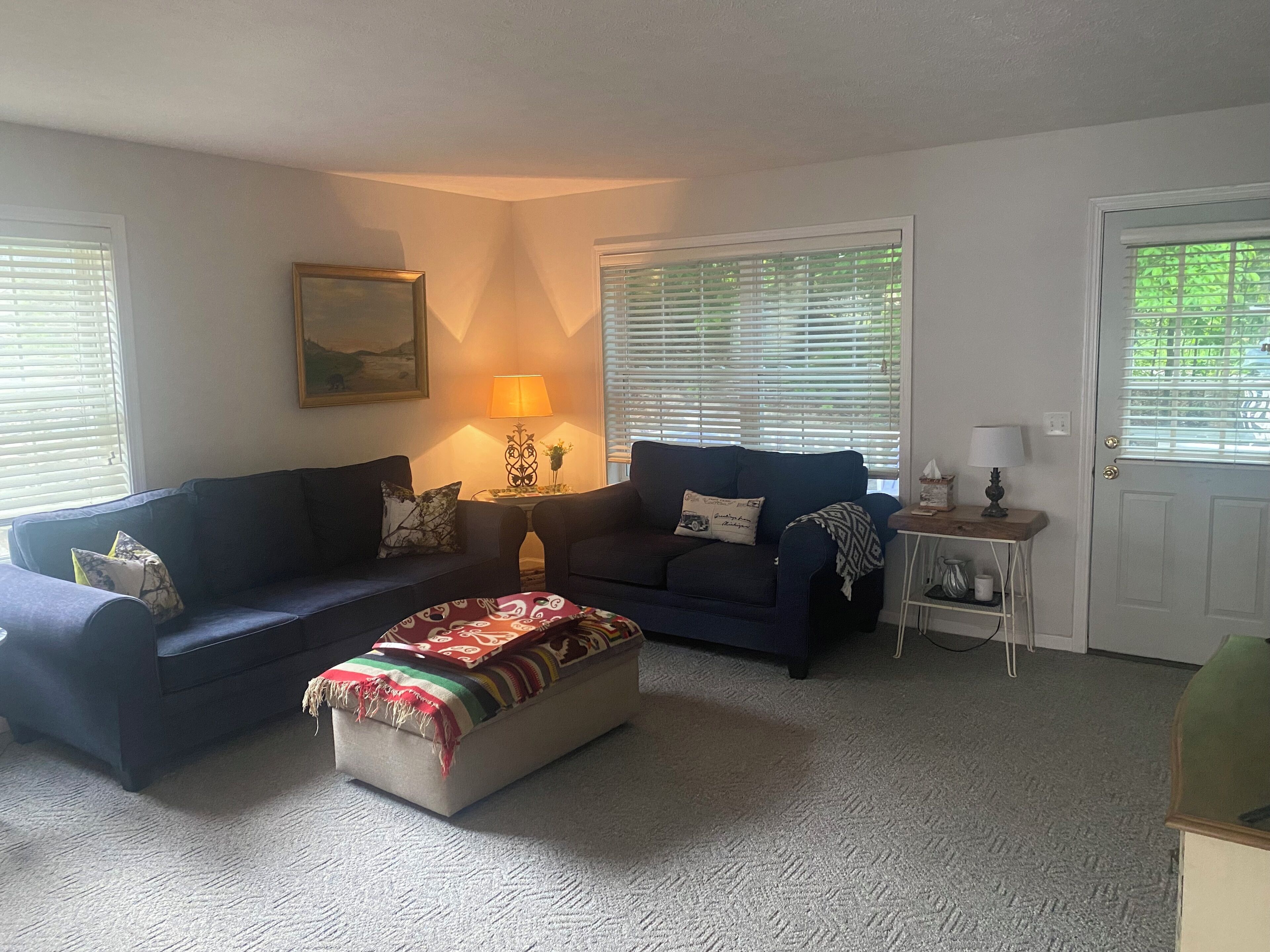 A living room with two sofas, a coffee table, a lamp, and a door.