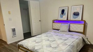 Ein Schlafzimmer mit einem Bett, einer Tür und zwei gerahmten Bildern an der Wand.