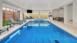 A swimming pool with a tiled edge and a turtle design, surrounded by lounge chairs and a barbecue area.