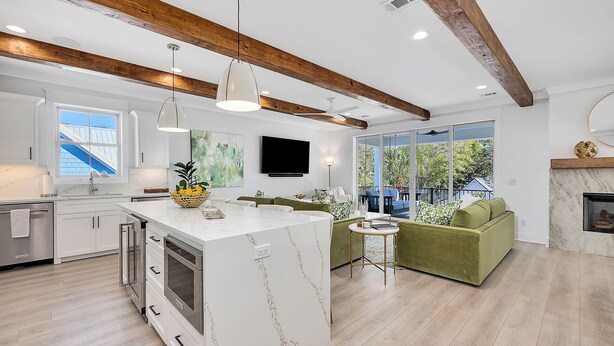 A modern kitchen with a central island, built-in appliances, and a dining area with a green sofa and a small table.