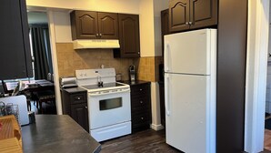 Una cocina moderna con armarios de madera oscura, una estufa blanca y un refrigerador grande.