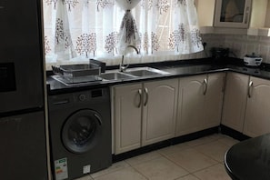 A kitchen with a washing machine, a sink, and cabinets.