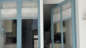 A narrow entrance with a white wall and a blue-framed door leading into a kitchen area with cabinets and a countertop. - 3Bed House- Sleeps 6 - Pool, Garden, Pets, Parking (Beauvais-sur-Matha)