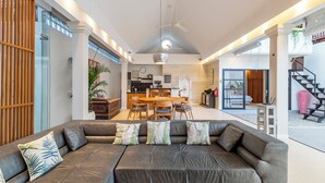 Un amplio espacio habitable con un sofá de cuero, una mesa de comedor y una cocina al fondo.