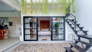 Un interior moderno con una cama, una escalera y plantas colgantes.