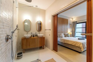 Een moderne badkamer met een glazen douchecabine, een houten wastafelmeubel en een grote spiegel.