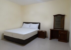 A bedroom with a bed, a nightstand, a dresser, and a mirror.