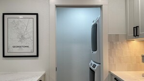 Un pasillo estrecho con una puerta que da a una zona de cocina. Un mapa enmarcado de Georgetown, Texas está colgado en la pared.