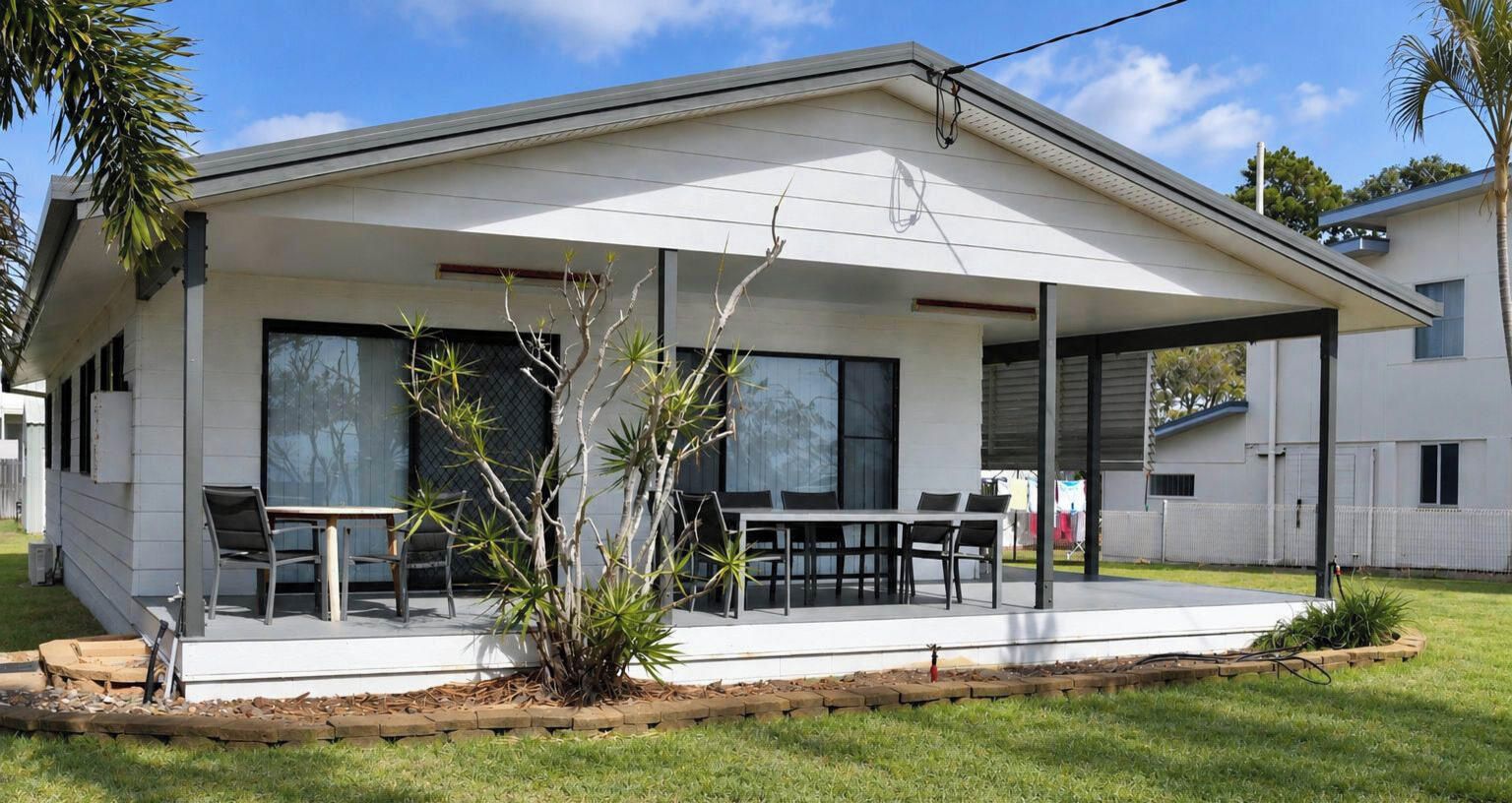 A modern house with a covered patio, large windows, and a well-maintained lawn.