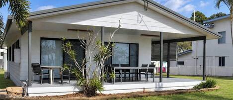 A modern house with a covered patio, large windows, and a well-maintained lawn.