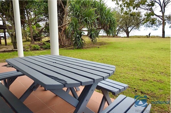 Enjoy a serene outdoor setting with a picnic table surrounded by lush greenery and a tranquil body of water.