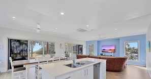 Enjoy a spacious living area with a large window offering a view of the surrounding landscape, a central island kitchen, and a comfortable seating area with a sofa and dining table.