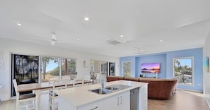 Enjoy a spacious living area with a large window offering a view of the surrounding landscape, a central island kitchen, and a comfortable seating area with a sofa and dining table.