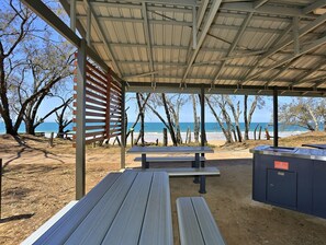 Relax in a shaded outdoor space with a bench and picnic table, overlooking a scenic beach view.
