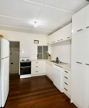 A compact kitchen with white cabinets, a stove, and a dishwasher.
