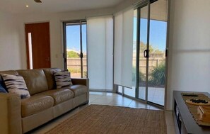 Relax in this stylish living room with a sofa, balcony access, and a view of lush greenery.