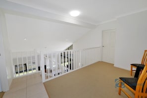 Enjoy a spacious room with a high ceiling, sloped design, and a seating area featuring two chairs.
