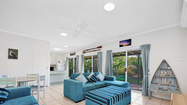 A modern living room with a sofa set, a dining table, and a kitchen area. - Spacious Open Plan Villa with Complex Pool (Woodgate)