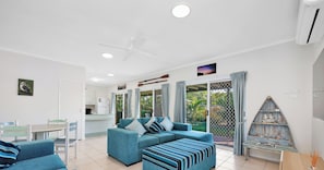 A modern living room with a sofa set, a dining table, and a kitchen area.