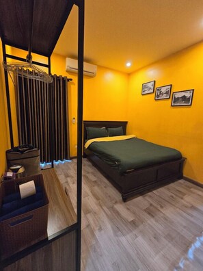 Un dormitorio con cama, un radiador, una cesta y una pared con tres cuadros.
