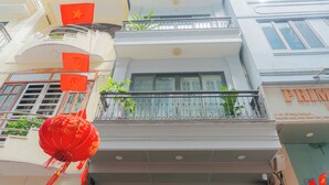 A multi-story building with balconies, windows, and a visible storefront with signage. - Dream Comes True (Hanoi)