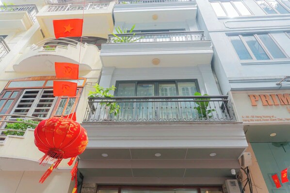 A multi-story building with balconies, windows, and a visible storefront with signage. - Dream Comes True (Hanoi)