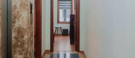 A hallway with a marble wall, a polished black floor, and a wooden door.