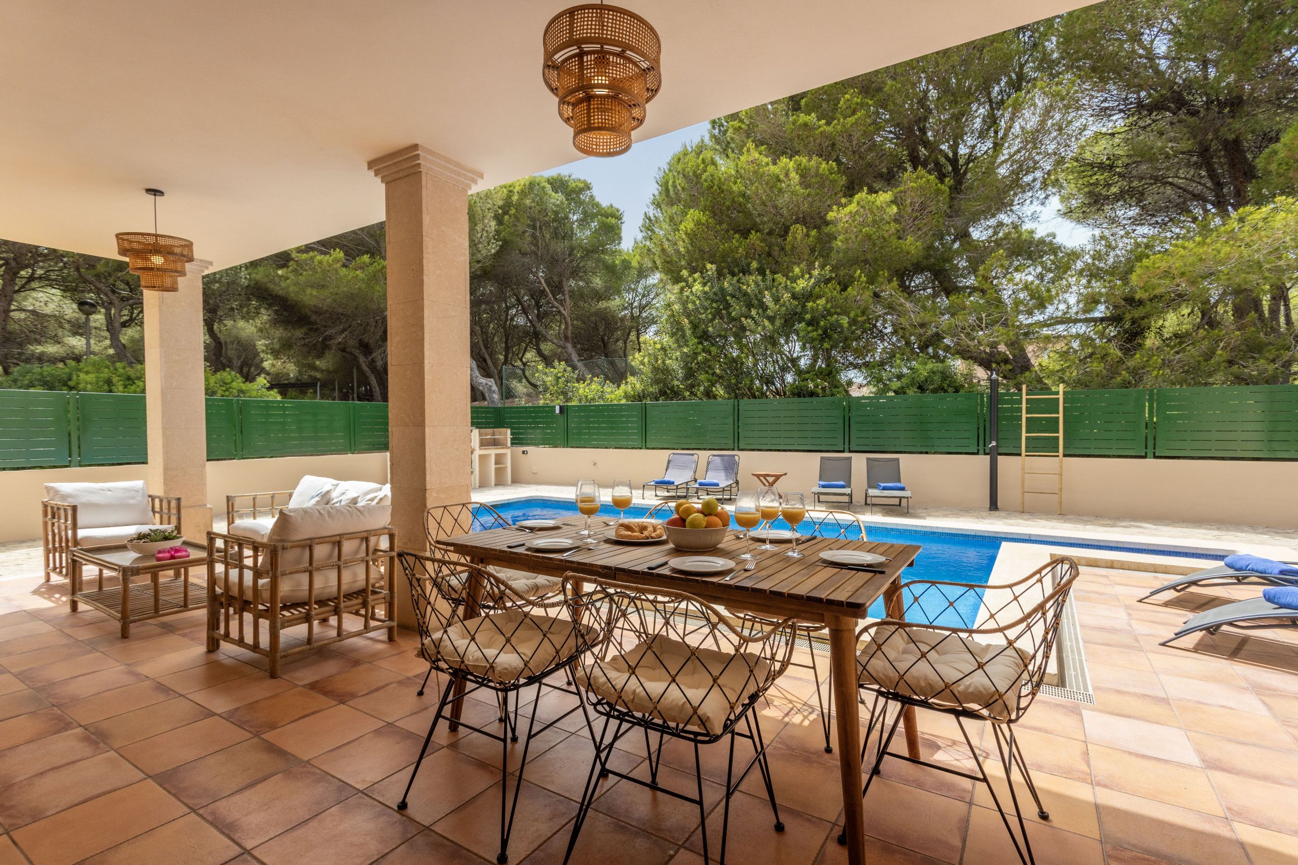 Zona exterior coberta amb piscina, taula de dinar, cadires i seients de relaxació.