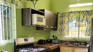 Een kleine keuken met een gasfornuis, oven, magnetron en houten kastjes.