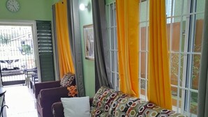 Een woonkamer met een gestreept sofa, een klok aan de muur en gordijnen voor de ramen.