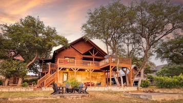 A wooden cabin with a balcony, outdoor seating, and a fire pit.