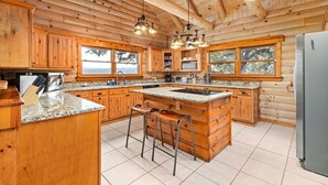 Eine geräumige Küche mit Holzschränken, Granit-Arbeitsplatten und einer großen Kochinsel mit Barhocker.