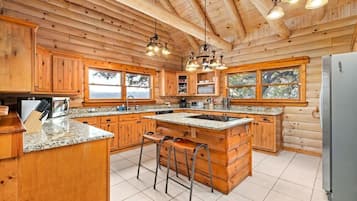 A spacious kitchen with wooden cabinets, granite countertops, and a large island with bar stools.