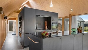 A modern kitchen with a large island, stainless steel appliances, and pendant lighting.