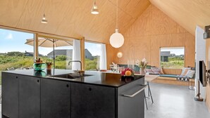 A modern kitchen with a large island, pendant lighting, and a view of the countryside.