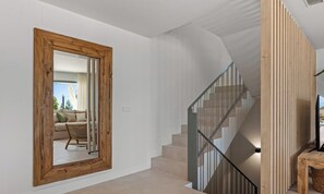 A modern interior with a wooden-framed mirror, a staircase with metal railings, and a woven basket. - Marisol | Sea View - Terrace - Pool (Mijas Costa)