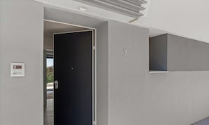 A modern interior with a black door, a small window, and a wall-mounted number.