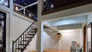 A spacious interior with a staircase leading to an upper level, a bench, and a small table with a basket. - Villa Gunung Bhakti (Cipanas)