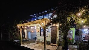 A small, illuminated structure with a glass enclosure, surrounded by plants and a water feature. - Villa Gunung Bhakti (Cipanas)