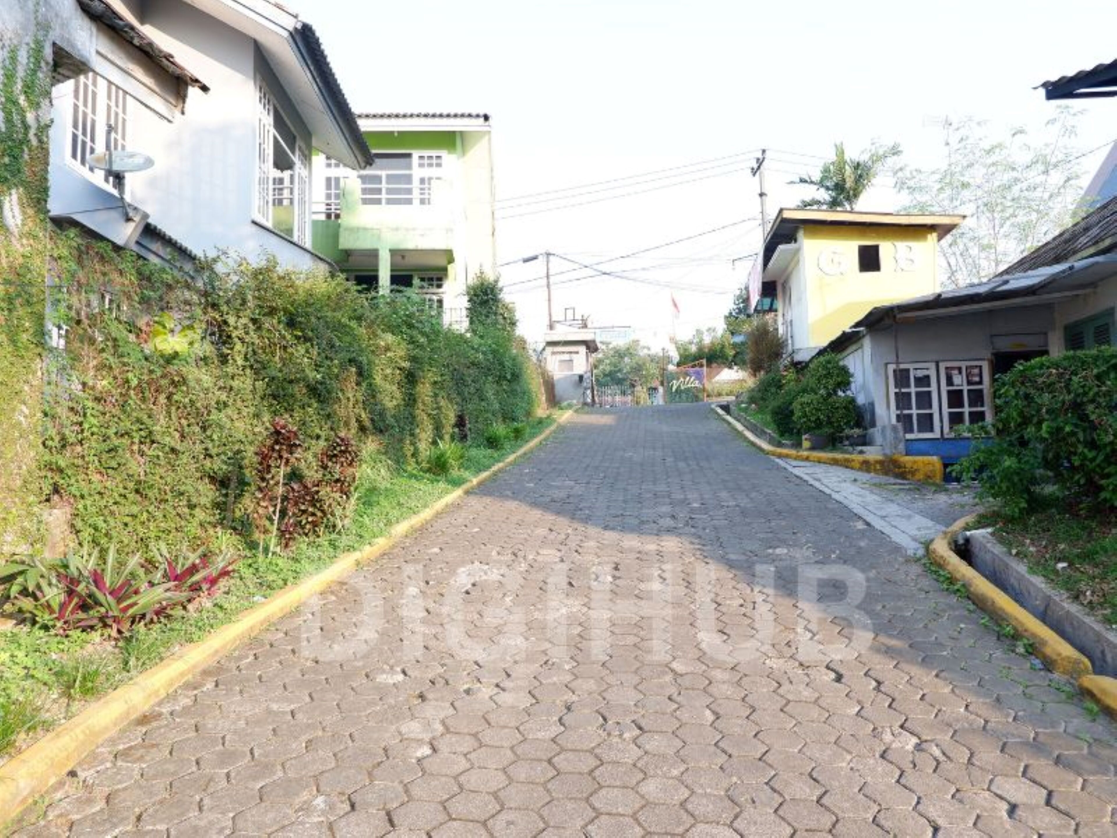 Calle empedrada bordeada de edificios residenciales, algunos con balcones y vegetación.