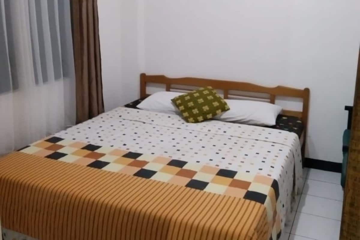 A neatly made bed with a checkered bedspread and a single pillow.