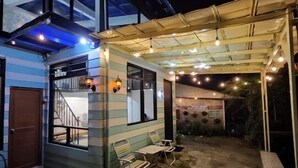 A covered outdoor area with a patio, a staircase leading to an upper level, and string lights. - Villa Gunung Bhakti (Cipanas)
