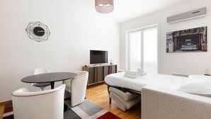 A modern hotel room with a bed, a desk, a chair, a TV, and a painting on the wall. - GuestHost - Beautiful 35 sqm apartment located on the mezzanine floor of a building WITHOUT elevator (stairs to access it). The property is located 11 minutes by public transport from City Life, the largest pedestrian area in Milan, and from MiCo, the la (Milano)