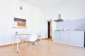 A modern kitchen with white cabinets, a tiled backsplash, and a dining area with a white table and chairs.