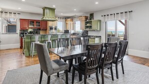 Una cocina moderna con zona de comedor, que incluye una isla grande, armarios de madera y vistas al exterior.